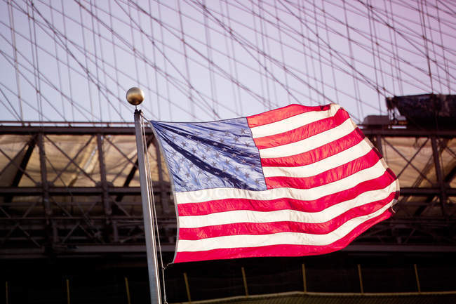 Bandera americana ondeando por puente urbano - foto de stock