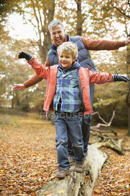 Мужчина и внук играют на бревне в парке — стоковое фото