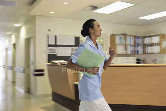Медсестра спешит в современный больничный коридор — стоковое фото