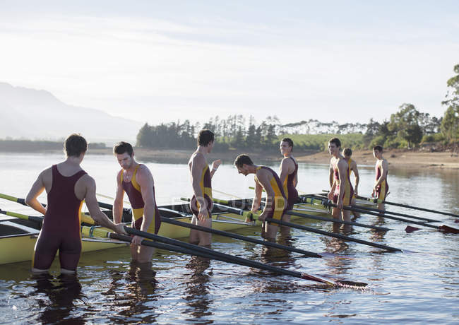 Équipe d'aviron plaçant le bateau sur le lac — Photo de stock