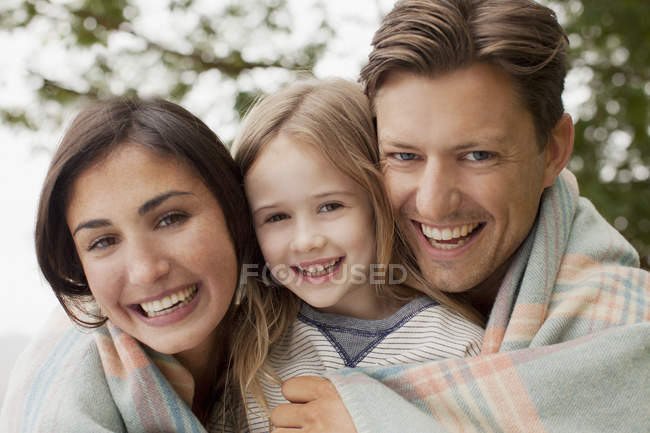 Close up portrait of smiling family wrapped in blanket — Stock Photo