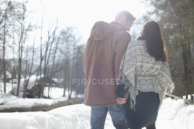 Couple holding hands and walking in snowy lane — Stock Photo