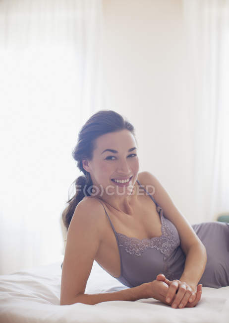 Retrato de mulher sorridente de camisola deitada na cama — Fotografia de Stock