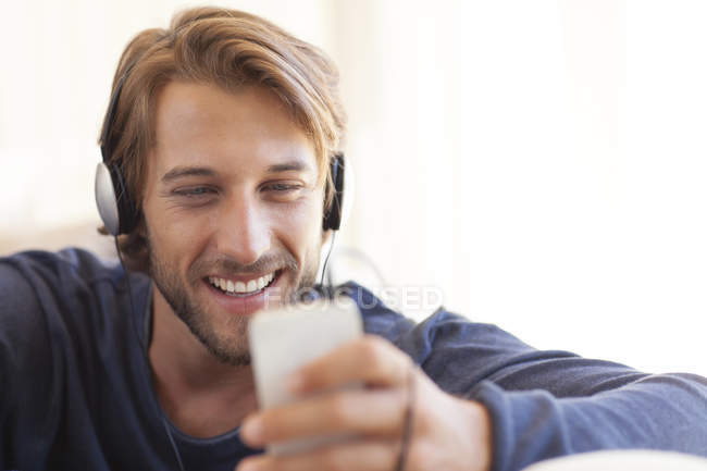 Jovem atraente Homem ouvindo fones de ouvido no sofá — Fotografia de Stock
