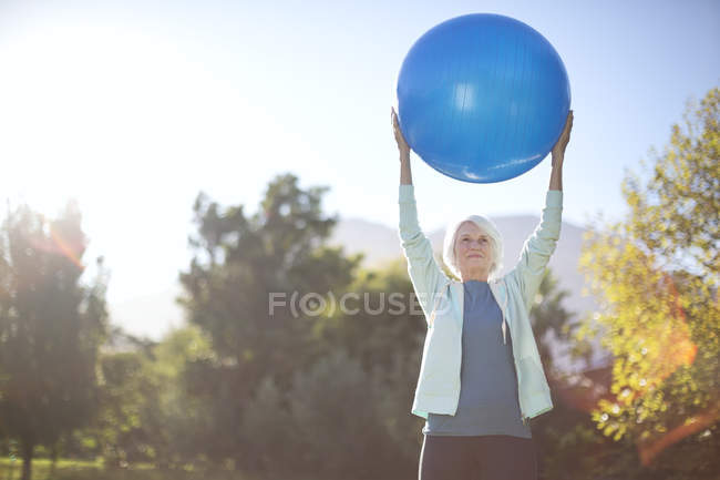 Senior woman holding fitness ball in park — Stock Photo