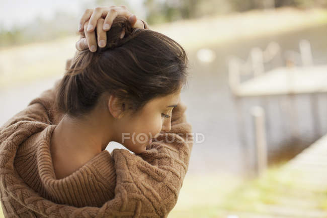 Donna con le mani nei capelli sul lungolago — Foto stock