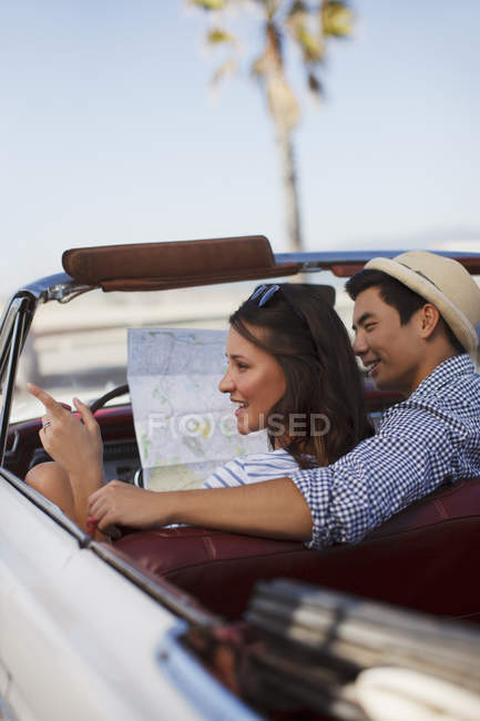 Sorrindo casal leitura mapa estrada conversível — Fotografia de Stock