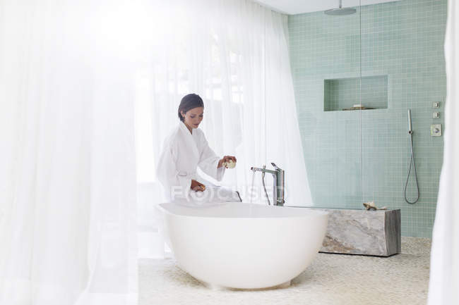 Женщина работает ванна в современной ванной комнате — стоковое фото