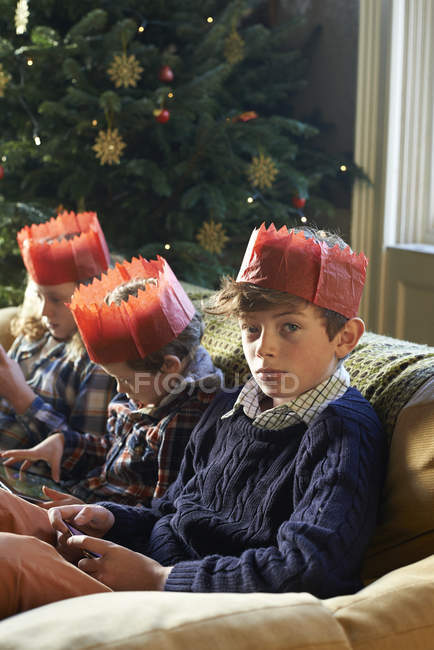 Crianças em coroas de papel relaxante no sofá — Fotografia de Stock