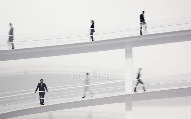 Pessoas de negócios desfocadas andando em passarelas elevadas — Fotografia de Stock