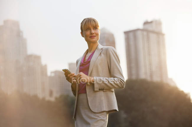 Mulher de negócios usando telefone celular no parque urbano — Fotografia de Stock