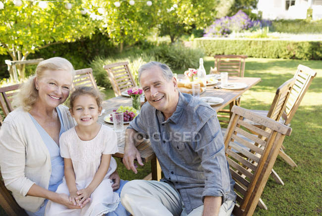 Couple plus âgé et petite-fille souriant à l'extérieur — Photo de stock
