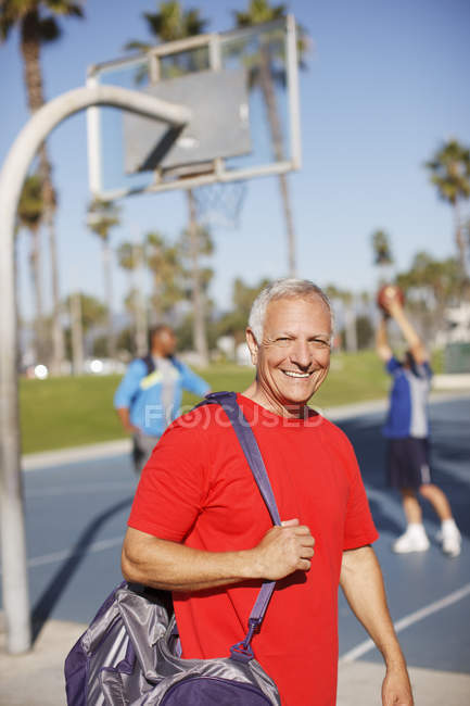 Older man carrying gym bag on court — Stock Photo