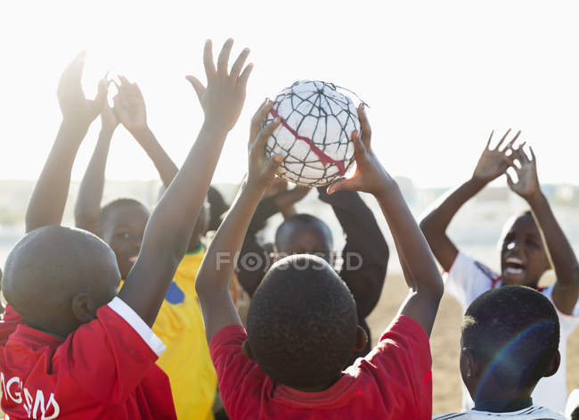 Garçons africains jouant au football ensemble dans un champ de terre — Photo de stock