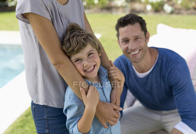 Счастливая семья улыбается на заднем дворе и смотрит в камеру — стоковое фото