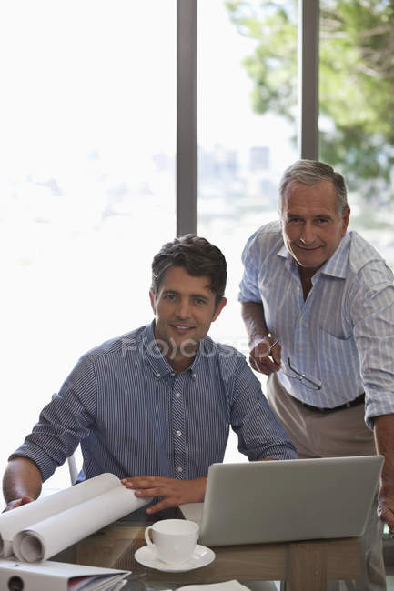 Hombre mayor y hombre más joven trabajando juntos en el escritorio - foto de stock