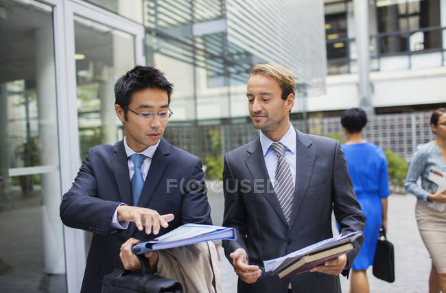 Des hommes d'affaires parlent à l'extérieur d'un immeuble de bureaux moderne — Photo de stock