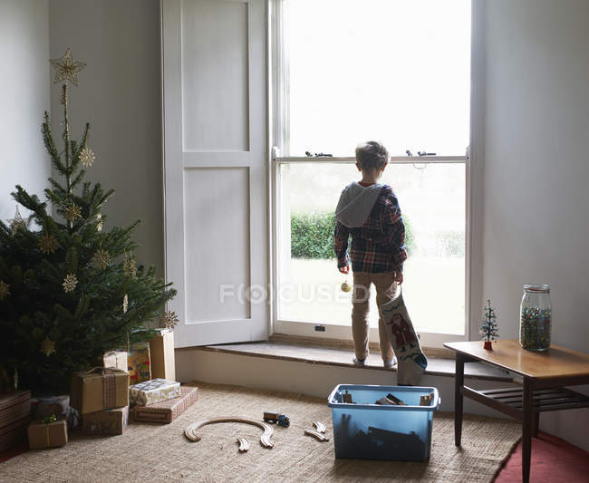 Junge hält Weihnachtsstrumpf am Fenster — Stockfoto