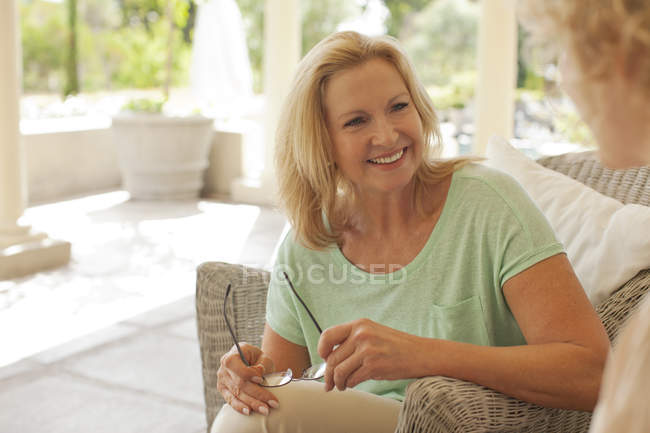 Smiling mother and daughter talking on porch — Stock Photo