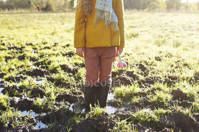 Ragazza raccolto in piedi in campo fangoso — Foto stock