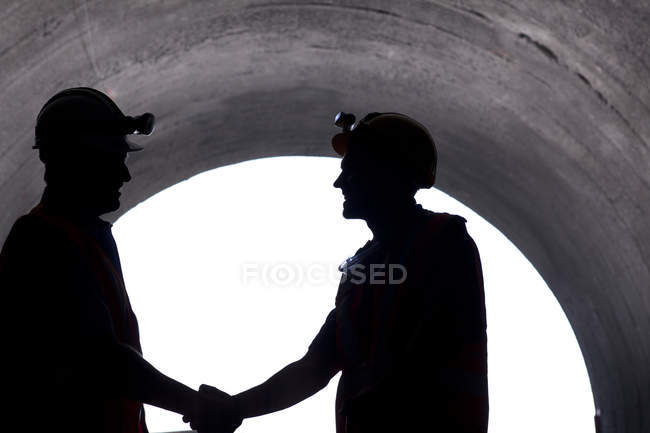 Silhouette von Arbeitern beim Händeschütteln im Tunnel — Stockfoto