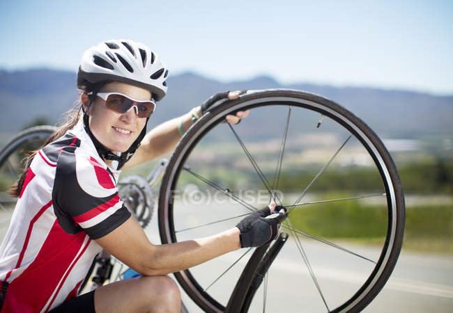 Велосипедист, регулюючи шини на сільській дорозі і, дивлячись на камеру — стокове фото