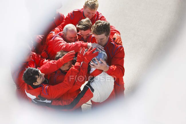 Racing team hugging racer at pit stop — Stock Photo