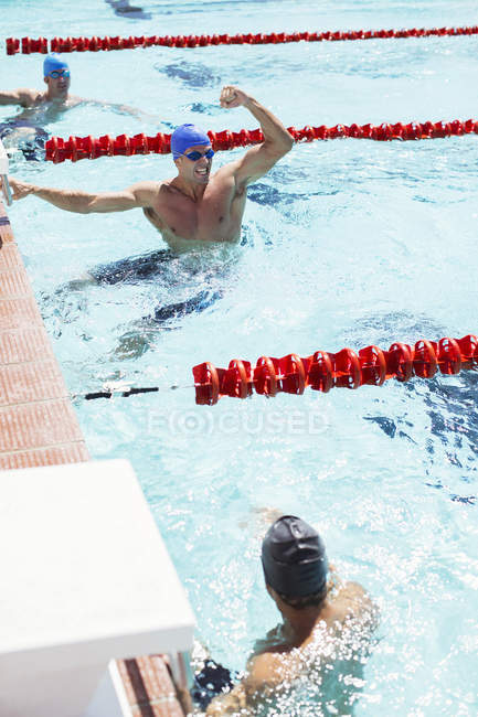 Nageur célébrant dans la piscine parmi d'autres hommes — Photo de stock