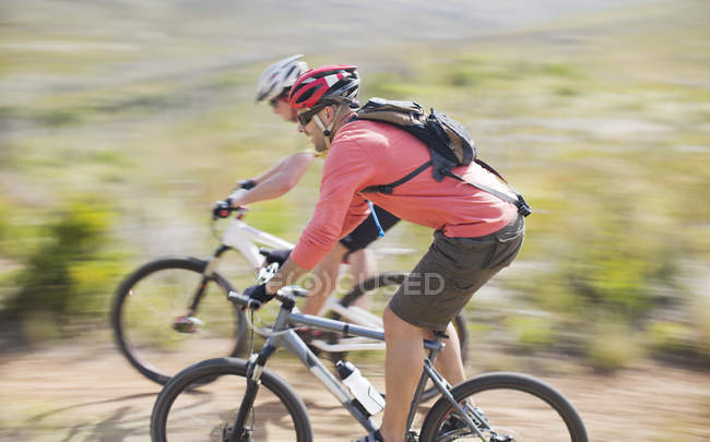 Visión borrosa de los ciclistas de montaña en el camino de tierra - foto de stock