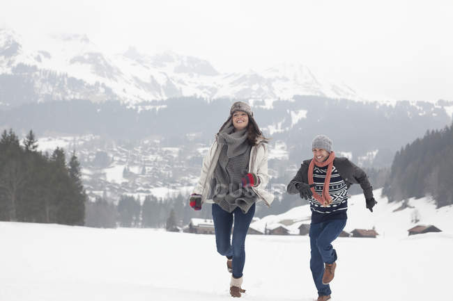 Щаслива пара біжить у засніженому полі — стокове фото