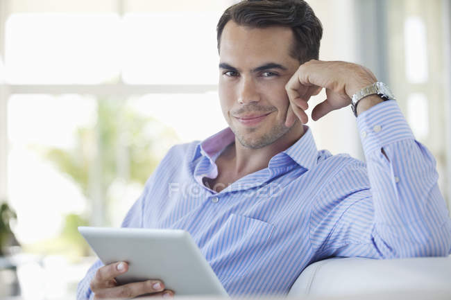 Homme d'affaires utilisant une tablette sur un canapé au bureau moderne — Photo de stock