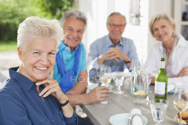 Друзья, улыбающиеся за столом на улице — стоковое фото