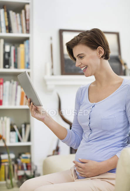 Беременная женщина с помощью планшетного компьютера — стоковое фото