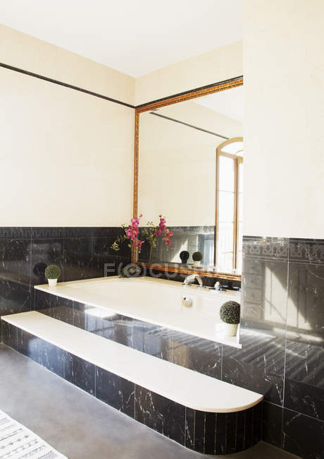 Черный мрамор окружающий ванну в роскошной ванной комнате — стоковое фото