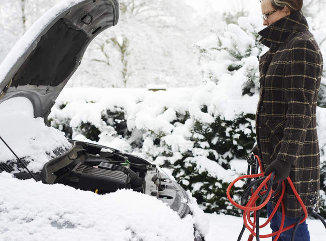 Donna che lavora su auto guasto nella neve — Foto stock