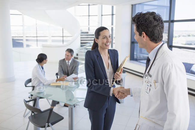 Médecin et femme d'affaires poignée de main en réunion — Photo de stock