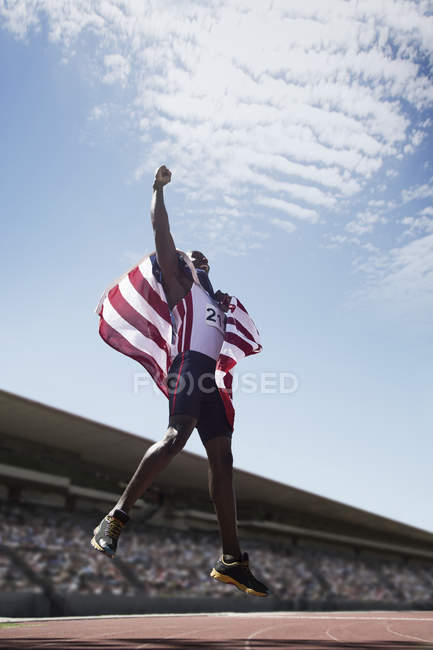 American track and field athlete cheering on track with American flag — Stock Photo