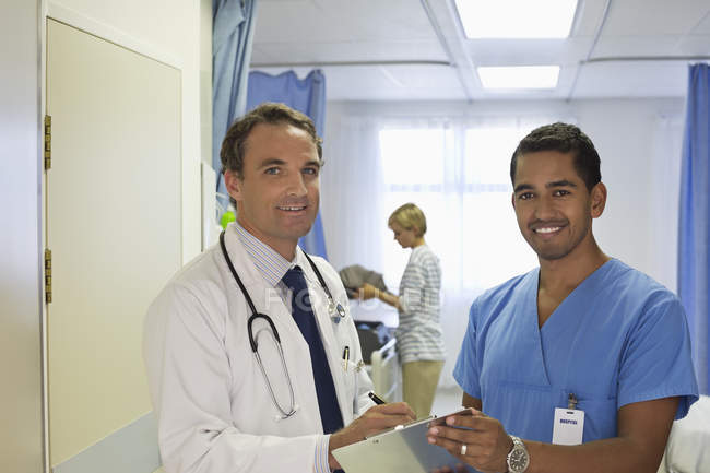 Médico e enfermeiro conversando no quarto do hospital — Fotografia de Stock