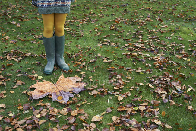 Crop girl standing by large autumn leaf — Stock Photo