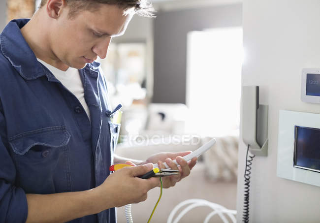 Habile électricien caucasien travaillant au téléphone à la maison — Photo de stock