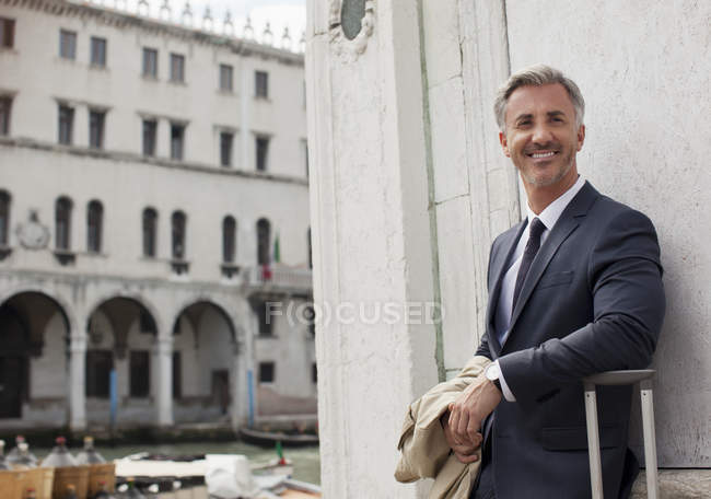 Портрет улыбающегося бизнесмена с чемоданом в Венеции — стоковое фото