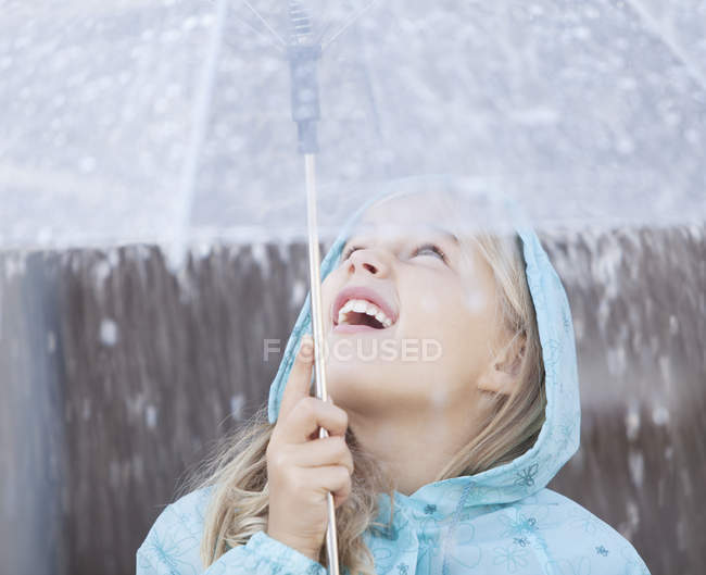 Close up of girl under umbrella looking up at downpour — Stock Photo
