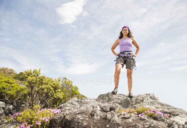 Альпинистка, стоящая на каменистой вершине холма — стоковое фото