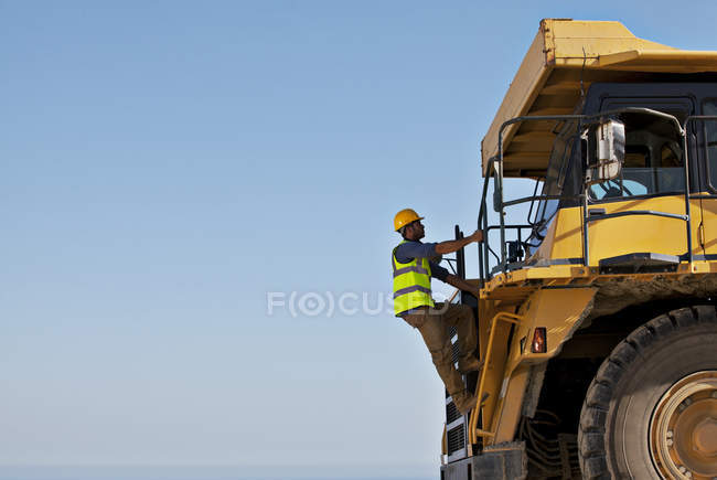 Worker climbing machinery on site — Stock Photo