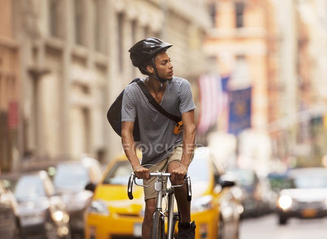 Hombre montar en bicicleta en la calle de la ciudad y mirando a un lado - foto de stock