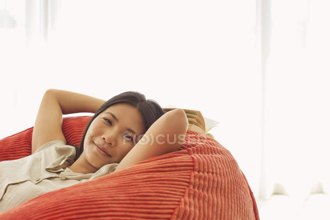 Jeune femme souriante attrayante se détendre dans une chaise de haricot — Photo de stock