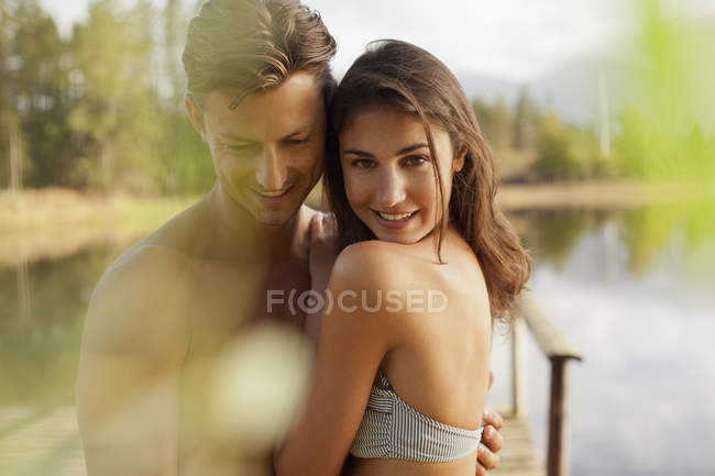 Портрет усміхненої пари, що обіймається на березі озера — стокове фото