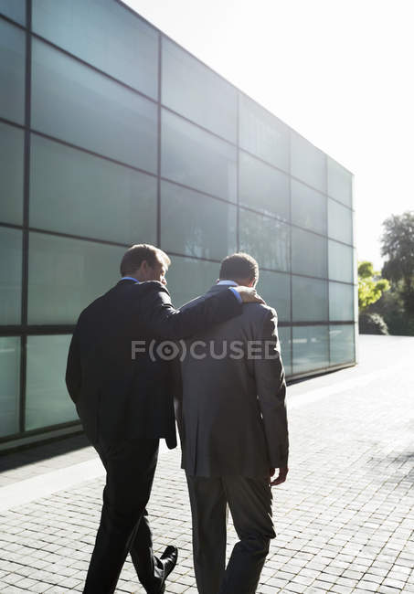 Vista trasera de los hombres de negocios hablando en la calle de la ciudad - foto de stock