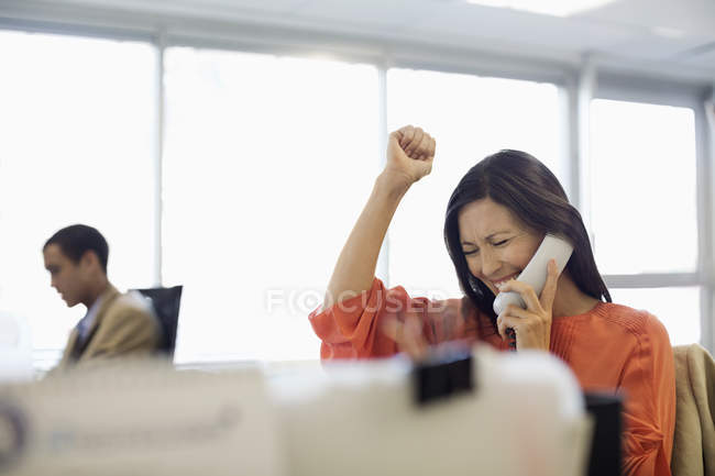 Businesswoman cheering at desk in office — Stock Photo