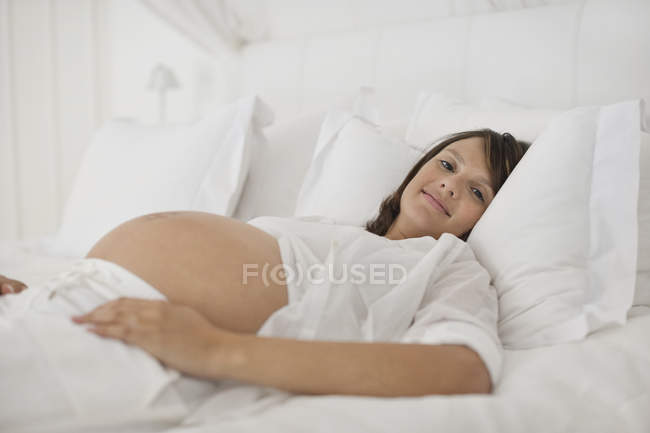 Schwangere liegt auf Bett — Stockfoto